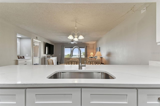 kitchen featuring white cabinets, sink, a textured ceiling, and hanging light fixtures