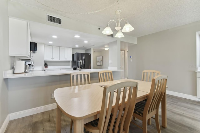 dining space with light wood-type flooring, a textured ceiling, and a chandelier