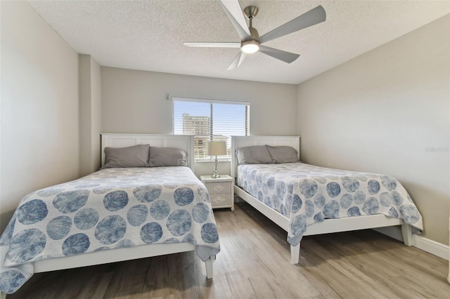 bedroom featuring ceiling fan, a textured ceiling, and light wood-type flooring