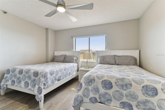 bedroom with hardwood / wood-style floors, ceiling fan, and a textured ceiling