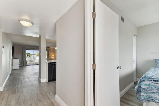 hall featuring a textured ceiling and light hardwood / wood-style flooring