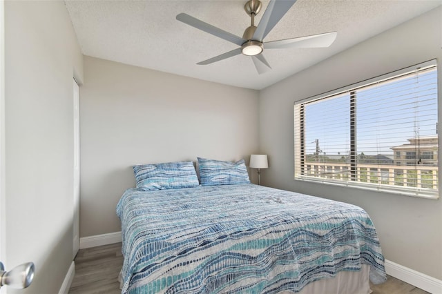 bedroom featuring ceiling fan, wood-type flooring, and a textured ceiling