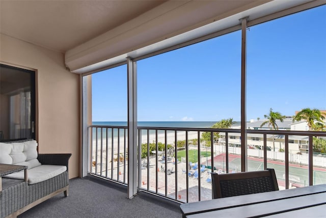 sunroom / solarium featuring a water view and a view of the beach