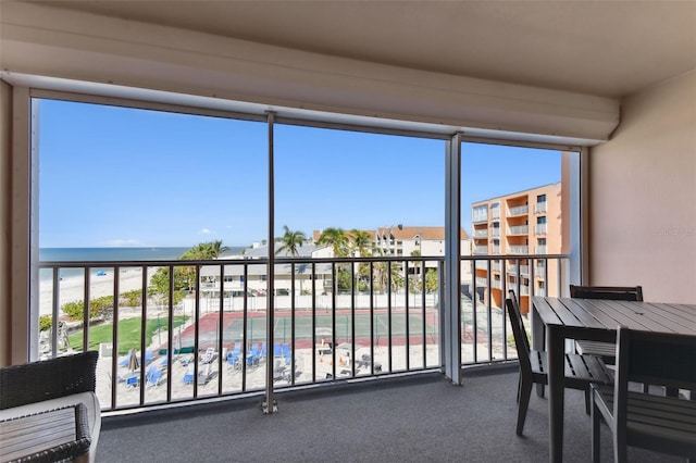 unfurnished sunroom with a beach view, a water view, and a healthy amount of sunlight