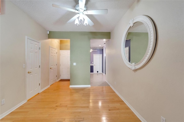 corridor with a textured ceiling and light hardwood / wood-style flooring