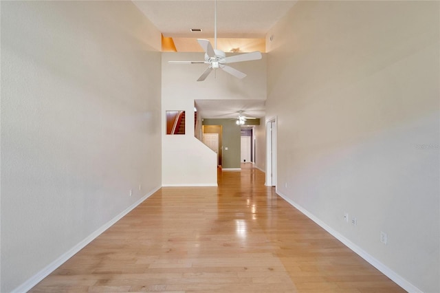 unfurnished room with a high ceiling, light hardwood / wood-style flooring, and ceiling fan