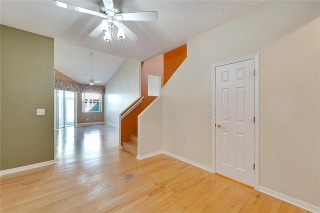 interior space with a textured ceiling, light wood-type flooring, ceiling fan, and lofted ceiling