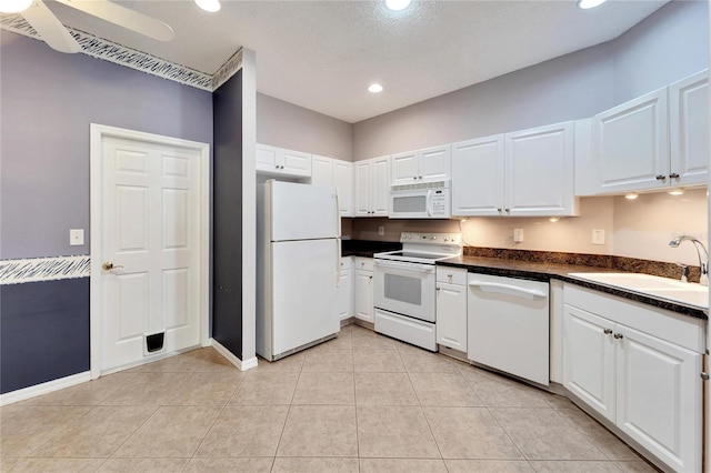 kitchen with white appliances, a textured ceiling, sink, light tile patterned floors, and white cabinets