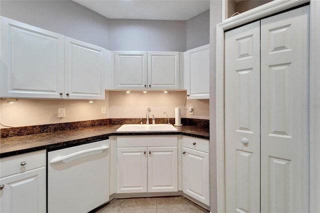 kitchen featuring white cabinetry, sink, white dishwasher, and light tile patterned flooring