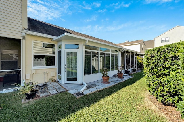 back of property with a sunroom and a yard