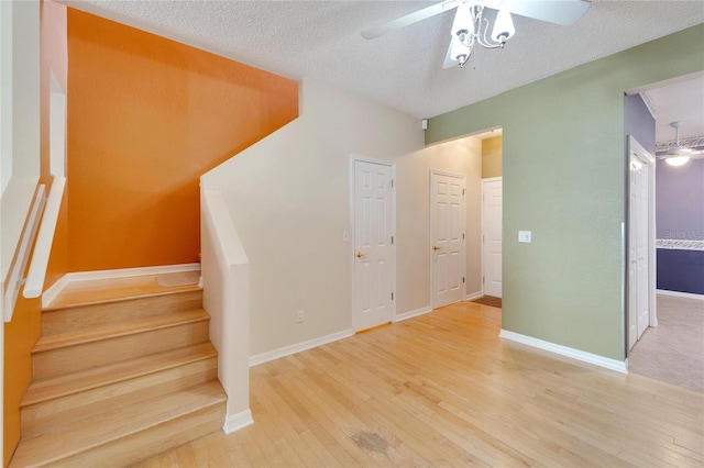 staircase with ceiling fan, a textured ceiling, and hardwood / wood-style flooring