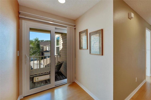 doorway featuring a textured ceiling and light hardwood / wood-style flooring