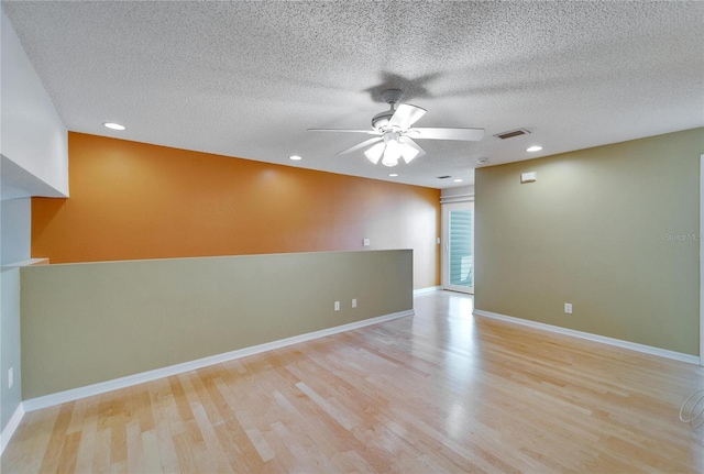 spare room featuring a textured ceiling, light hardwood / wood-style flooring, and ceiling fan