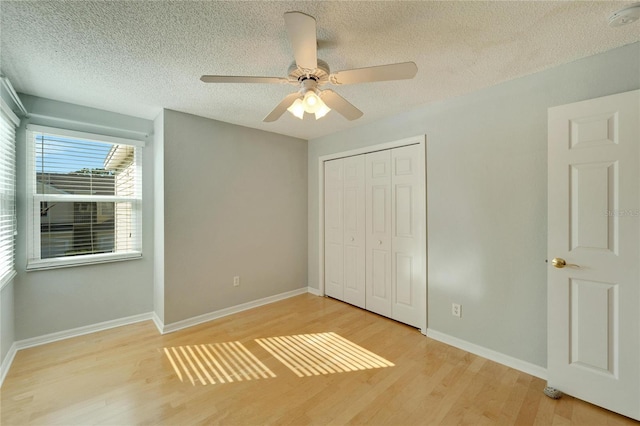 unfurnished bedroom featuring a textured ceiling, a closet, light hardwood / wood-style flooring, and ceiling fan