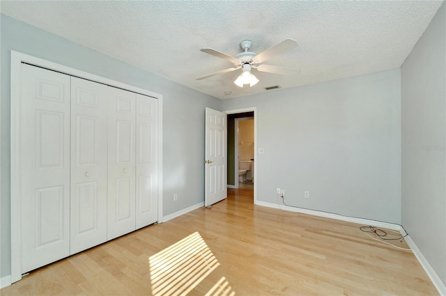 unfurnished bedroom with ceiling fan, a closet, a textured ceiling, and light hardwood / wood-style flooring