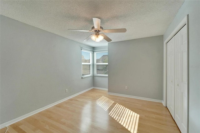 unfurnished bedroom with ceiling fan, light wood-type flooring, a textured ceiling, and a closet