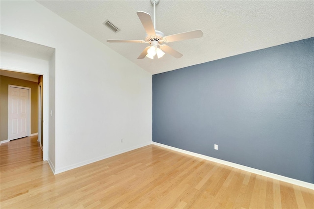 empty room with a textured ceiling, light wood-type flooring, vaulted ceiling, and ceiling fan