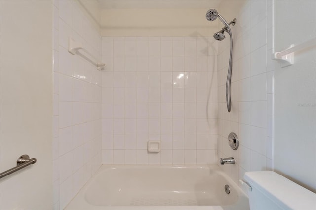 bathroom featuring tiled shower / bath combo and toilet