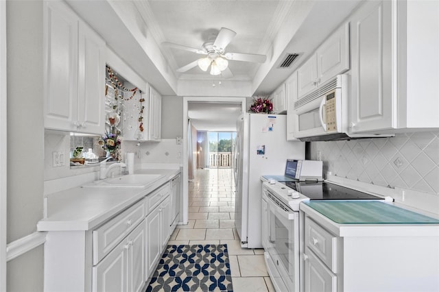 kitchen featuring decorative backsplash, white appliances, a tray ceiling, sink, and white cabinets