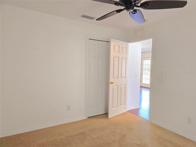 unfurnished bedroom featuring a closet, ceiling fan, and light colored carpet