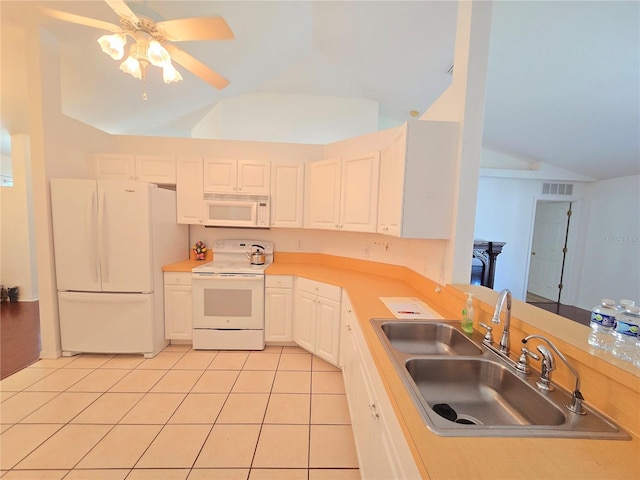 kitchen with lofted ceiling, sink, white appliances, light tile patterned floors, and white cabinets