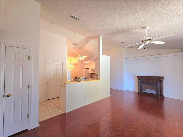 unfurnished living room with a textured ceiling, lofted ceiling, ceiling fan, and light hardwood / wood-style flooring