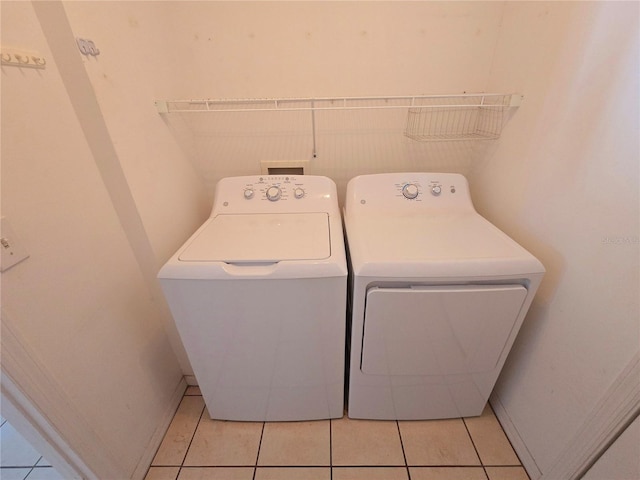 laundry area with independent washer and dryer and light tile patterned floors