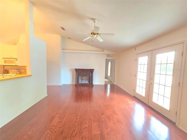 unfurnished living room with ceiling fan, french doors, wood-type flooring, and vaulted ceiling