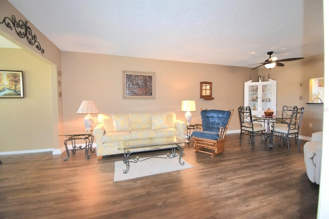 living room with dark hardwood / wood-style floors, ceiling fan, and a textured ceiling