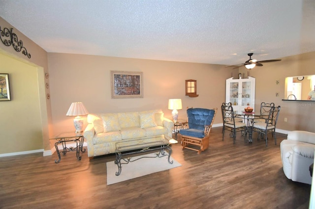 living room with ceiling fan, dark wood-type flooring, and a textured ceiling