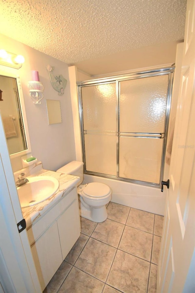 full bathroom with vanity, tile patterned flooring, toilet, enclosed tub / shower combo, and a textured ceiling