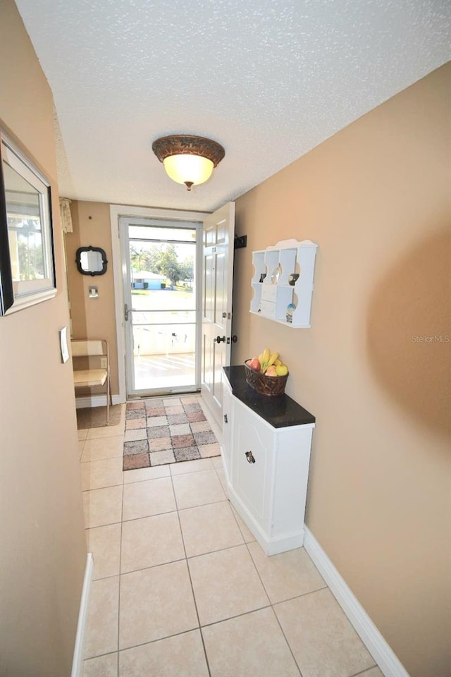 doorway to outside featuring light tile patterned floors and a textured ceiling