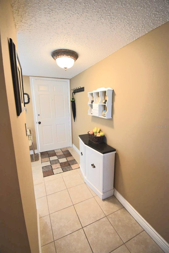 doorway with light tile patterned flooring and a textured ceiling