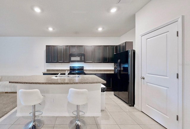 kitchen with black appliances, a kitchen breakfast bar, a kitchen island with sink, and sink