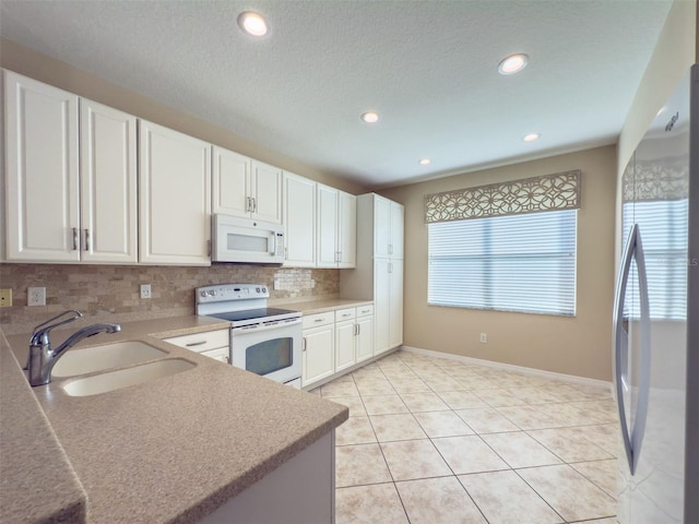 kitchen featuring sink, white appliances, white cabinetry, light tile patterned flooring, and decorative backsplash