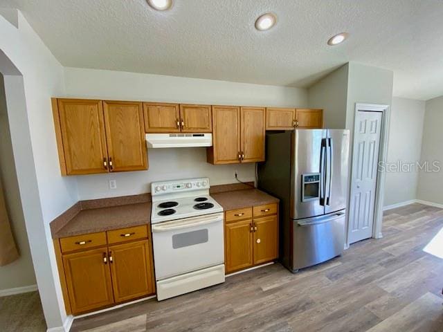 kitchen with white range with electric cooktop, stainless steel fridge, light hardwood / wood-style floors, and a textured ceiling