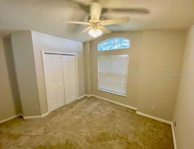 unfurnished bedroom with carpet flooring, ceiling fan, vaulted ceiling, and a closet