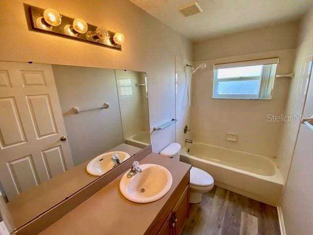 full bathroom featuring hardwood / wood-style floors, vanity, shower / bath combination, and toilet