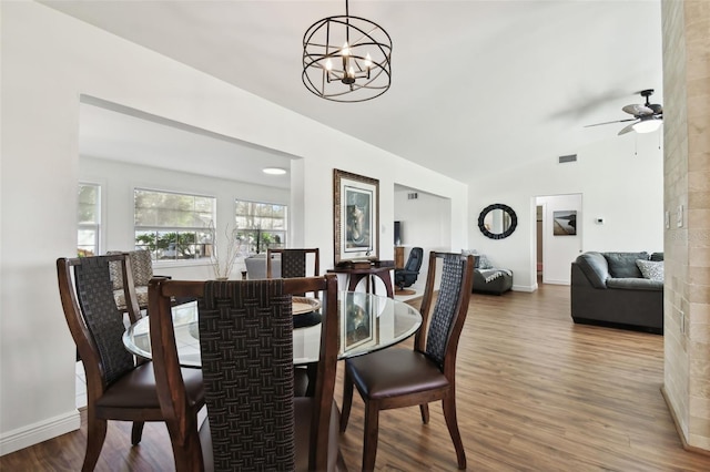 dining space featuring hardwood / wood-style flooring, ceiling fan with notable chandelier, and lofted ceiling