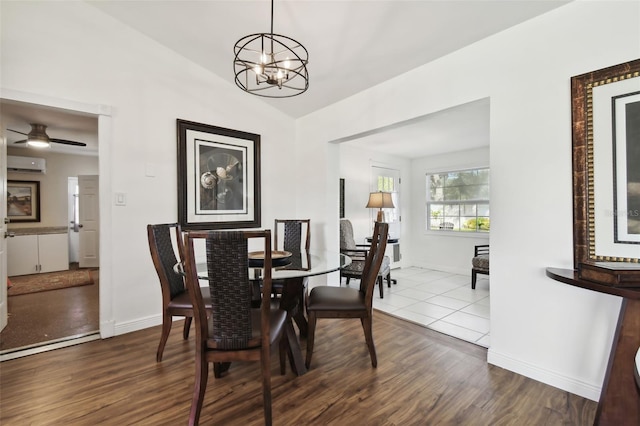 dining area featuring vaulted ceiling, hardwood / wood-style floors, ceiling fan with notable chandelier, and a wall mounted air conditioner