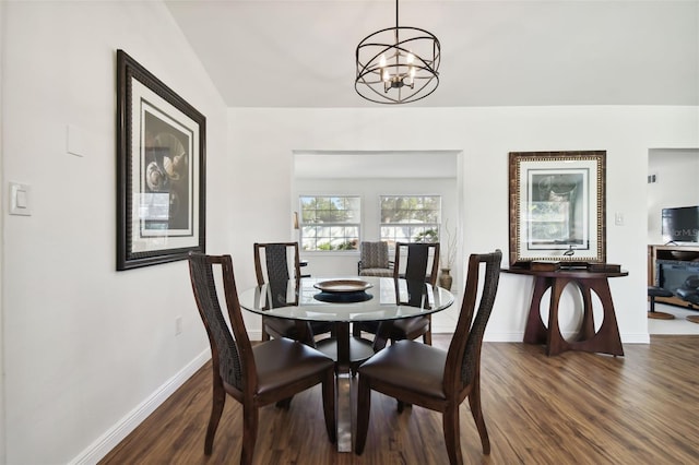 dining area featuring dark hardwood / wood-style floors, vaulted ceiling, and a chandelier