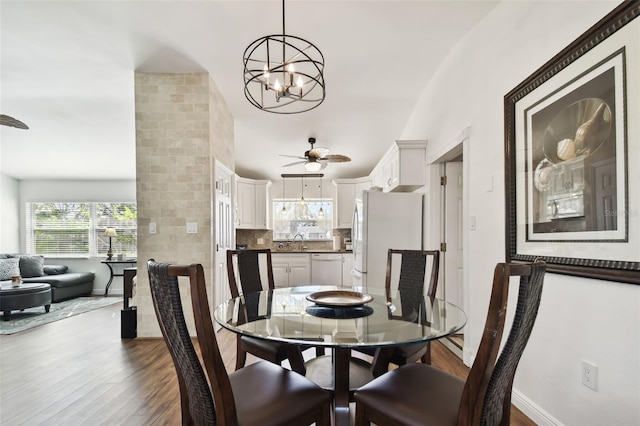 dining area with hardwood / wood-style floors, ceiling fan with notable chandelier, and sink