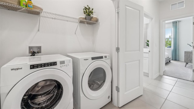 clothes washing area with light tile patterned flooring and independent washer and dryer