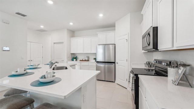 kitchen featuring white cabinets, a kitchen island with sink, sink, and appliances with stainless steel finishes