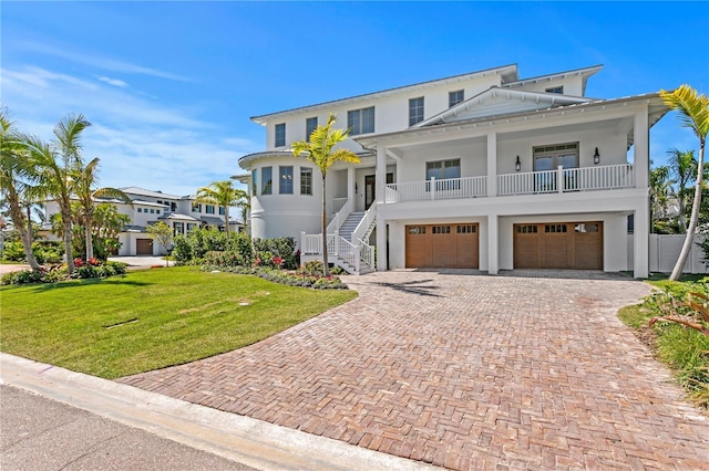 coastal home with a front lawn, decorative driveway, a garage, and stucco siding