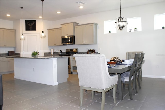 kitchen featuring a center island, tile patterned flooring, dark stone countertops, decorative light fixtures, and appliances with stainless steel finishes