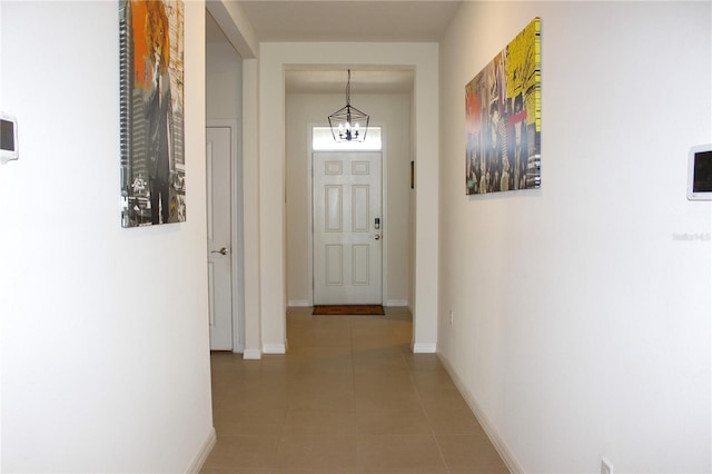 corridor with tile patterned flooring and a chandelier