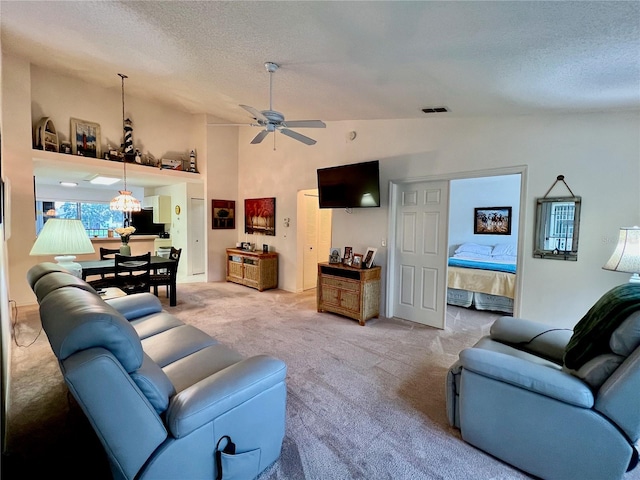 living room featuring a textured ceiling, ceiling fan, light carpet, and vaulted ceiling