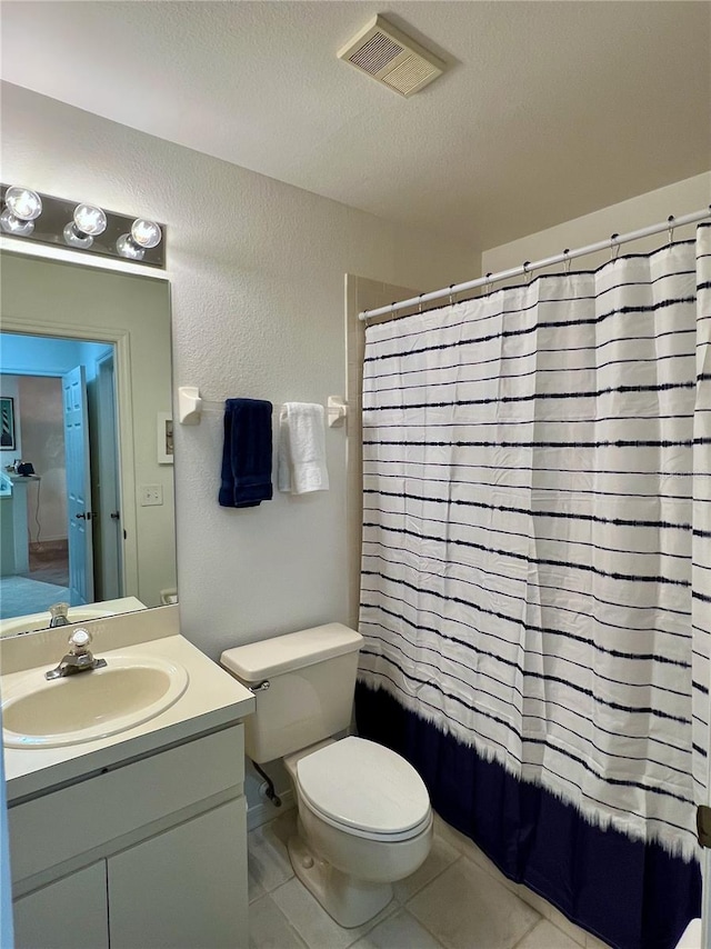 bathroom with tile patterned flooring, vanity, a textured ceiling, and toilet