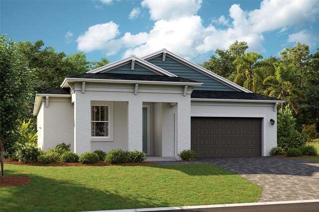 view of front of house with an attached garage, a shingled roof, a front lawn, and decorative driveway